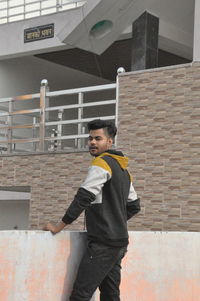 Full length of young man standing against brick wall