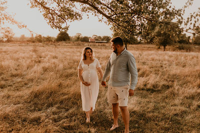 Rear view of couple walking on field