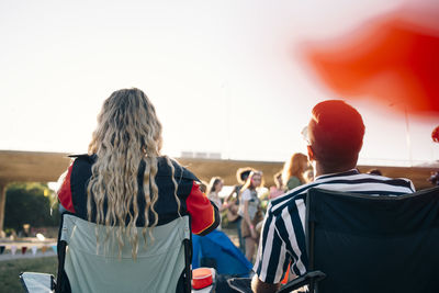 Rear view of man and woman looking at performers in music festival