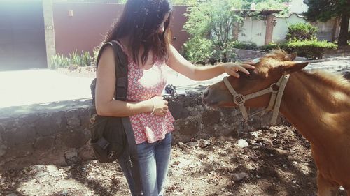 Full length of young woman standing by horse