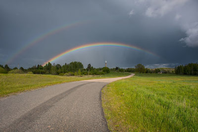 Scenic view of rainbow over road against sky