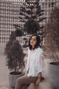 Portrait of young woman standing against wall