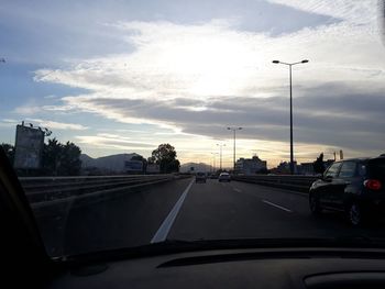 Cars on road against sky seen through car windshield