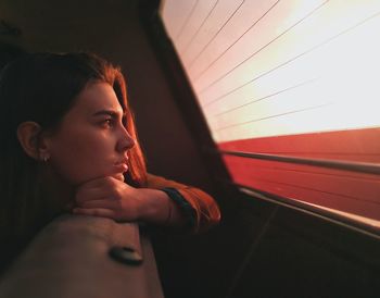 Thoughtful young woman looking through window while traveling in vehicle