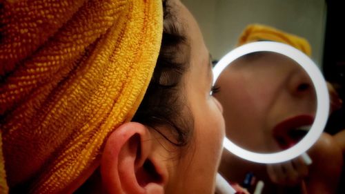 Reflection of woman on mirror in bathroom at home