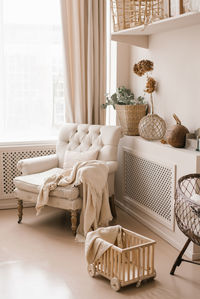 The living room is decorated in beige tones. a chair with a blanket and decor on the shelves 