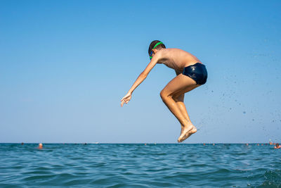 Full length of boy jumping in sea