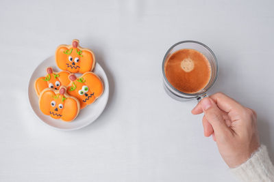 Cropped image of hand holding coffee cup against white background