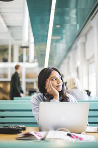 Thoughtful young female student sitting at cafeteria in university