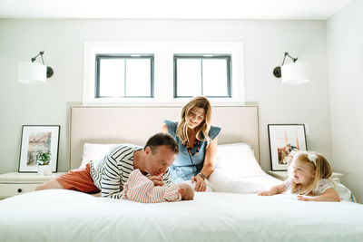 A new family of four playing together in a modern bedroom