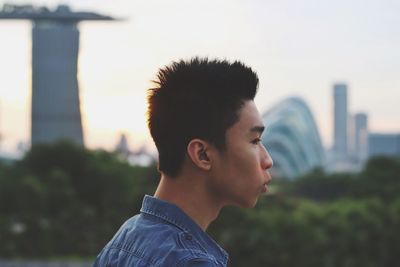 Close-up of young woman in city against sky