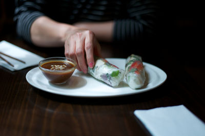 Midsection of woman holding ice cream in plate on table
