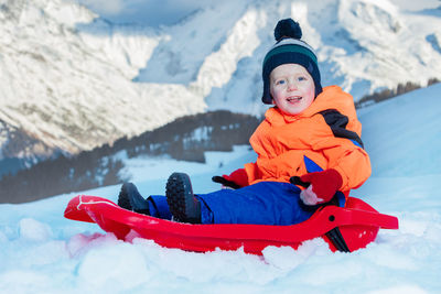 Portrait of smiling boy sitting on snow