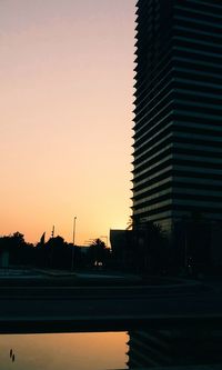 Silhouette buildings against clear sky at sunset