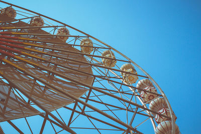 Low angle view of ferris wheel against clear blue sky