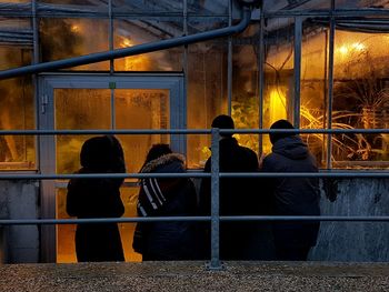 Rear view of a man sitting at illuminated building