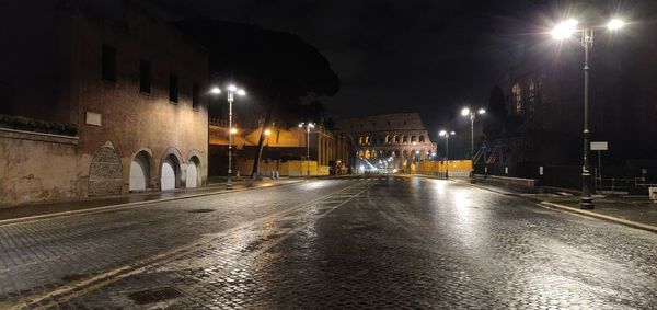 Illuminated street amidst buildings in city at night