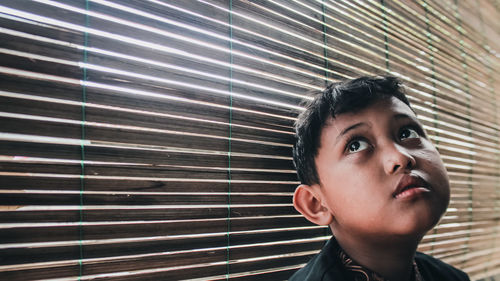 Close-up of young boy looking through window