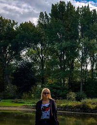 Portrait of woman standing by trees against plants