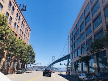 Cars on road amidst buildings against clear sky