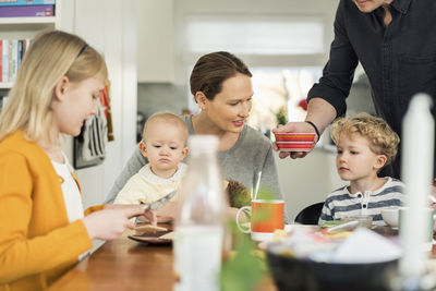 Family eating breakfast at table in living room