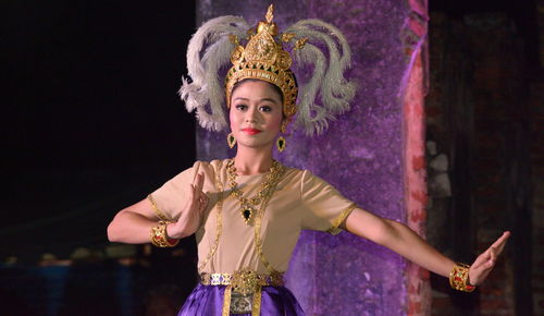 Portrait of young woman dancing against purple wall