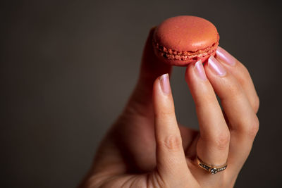 Midsection of woman holding macarons against black background