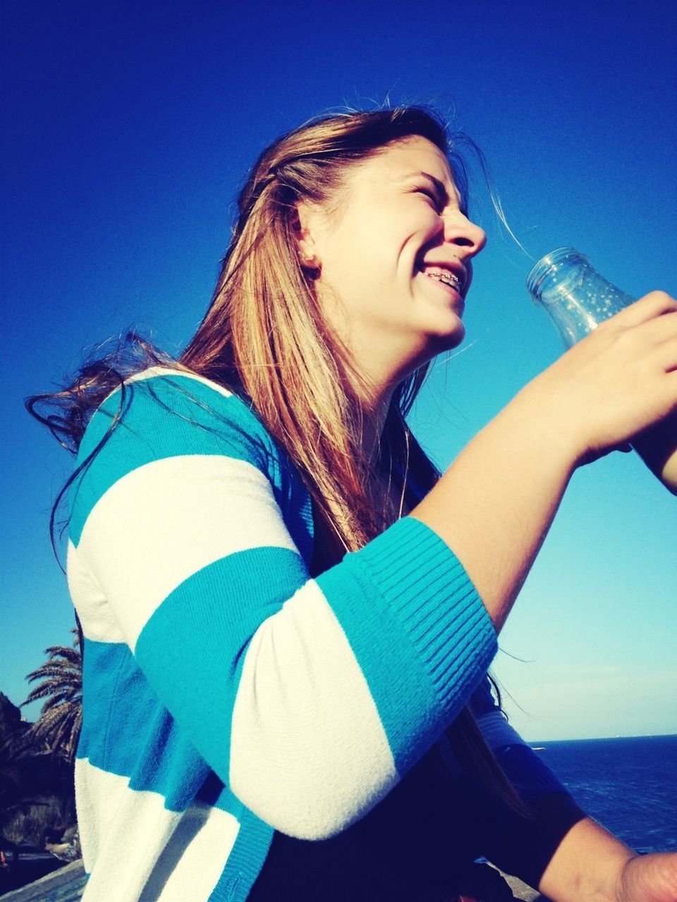 blue, person, young adult, lifestyles, clear sky, leisure activity, casual clothing, portrait, front view, looking at camera, young women, sunlight, smiling, sunglasses, copy space, happiness, water, day