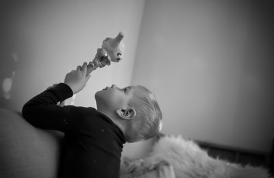 Portrait of cute boy with toy on bed at home