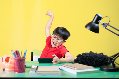 Portrait of boy sitting on table against wall