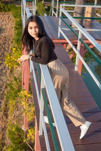 Portrait of woman smiling while sitting on railing