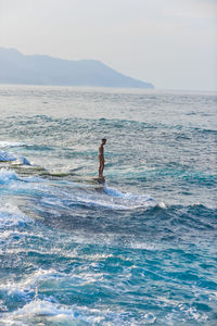 Man swimming in sea against sky