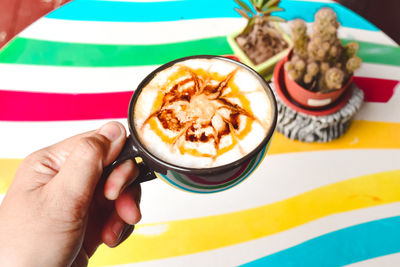 Close-up of hand holding coffee cup on table