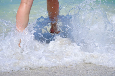 Low section of person splashing water in sea
