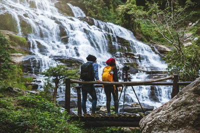 Rear view of waterfall amidst rocks against mountain