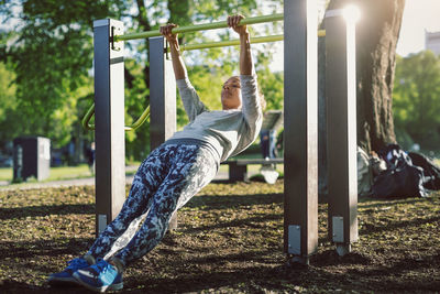 Low angle view of woman exercising on railing at park