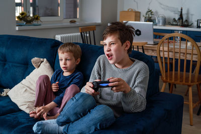 Boy looking at camera while sitting on sofa