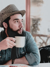 Portrait of young man looking away drinking coffee