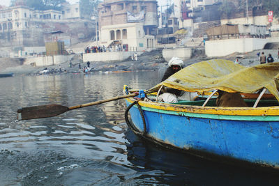 Row boat moving on ganges river with varanasi in background 