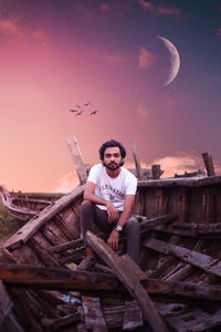 Full length of smiling young man sitting against sky