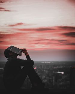 Rear view of woman photographing against sky during sunset