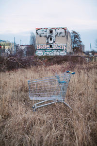 Abandoned shopping cart on field against sky at dusk