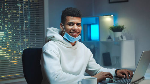 Portrait of young man using mobile phone at home