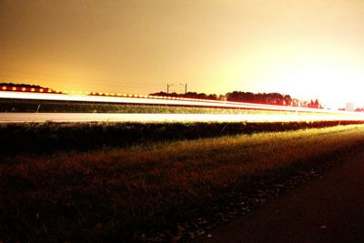 Road by field against clear sky at night