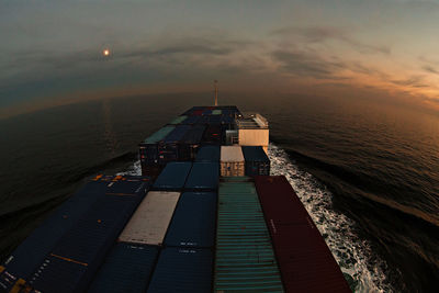 High angle view of container ship on sea during dusk