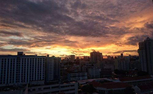 Cityscape against cloudy sky during sunset