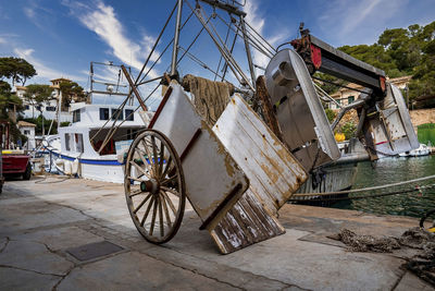 Machinery on boat lifting wagon on promenade against sky in town