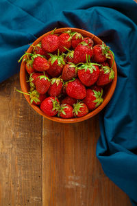 Fresh large strawberries in a clay plate on a wooden table. vertical photo