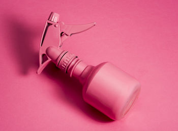 Close-up of pink spray bottle against colored background