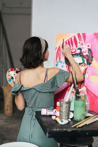 Rear view of woman painting on canvas at art studio